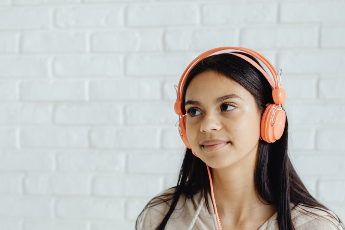 Young girl stares off to her left with a slight smile on her face with headphones on