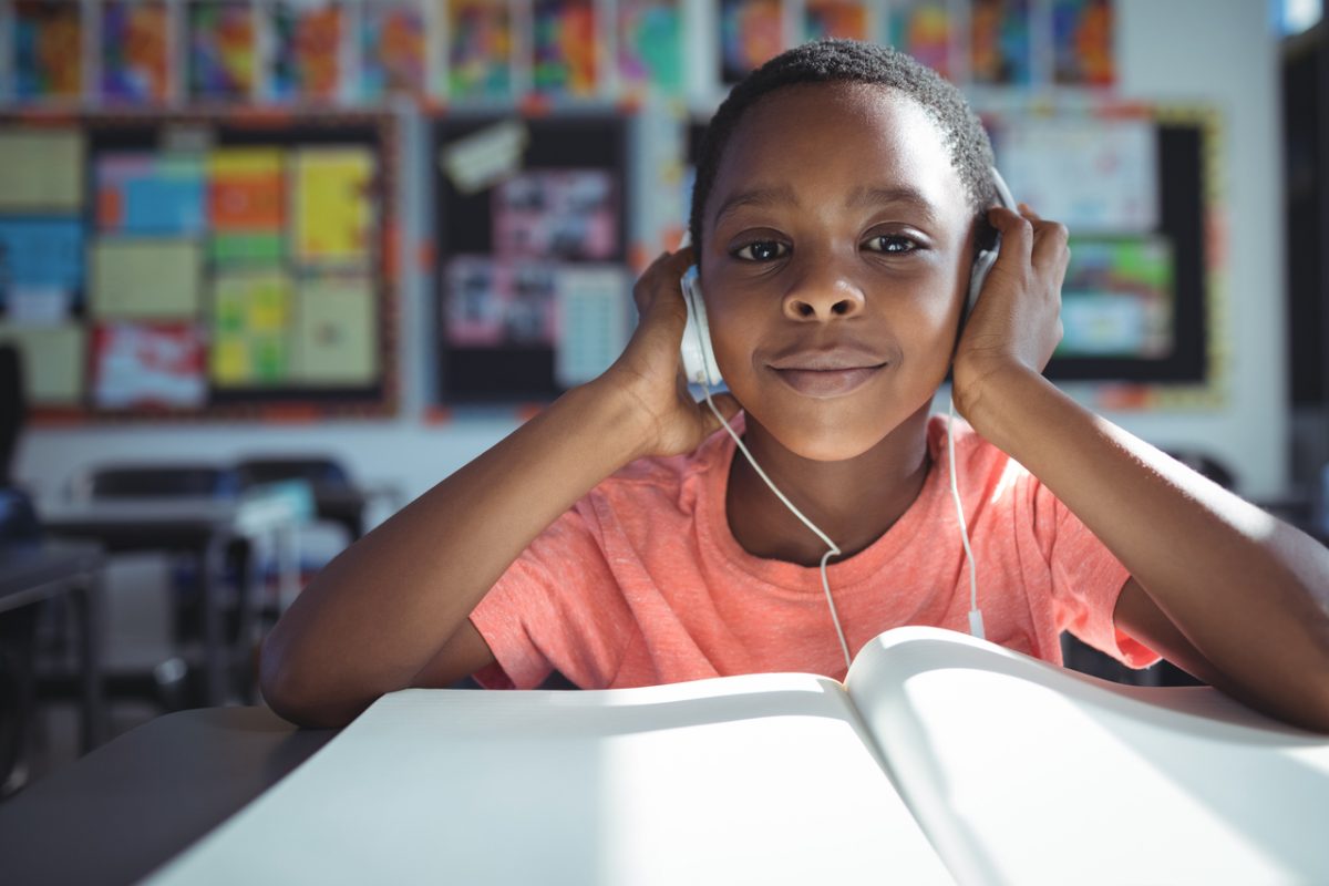 Portrait,Of,Boy,Listening,Music,With,Headphones,At,Desk,In